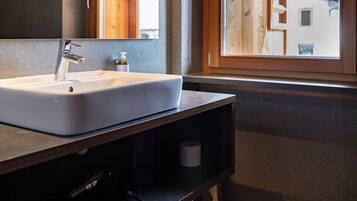 A bathroom with a large sink, a mirror, and a window with a view of mountains.
