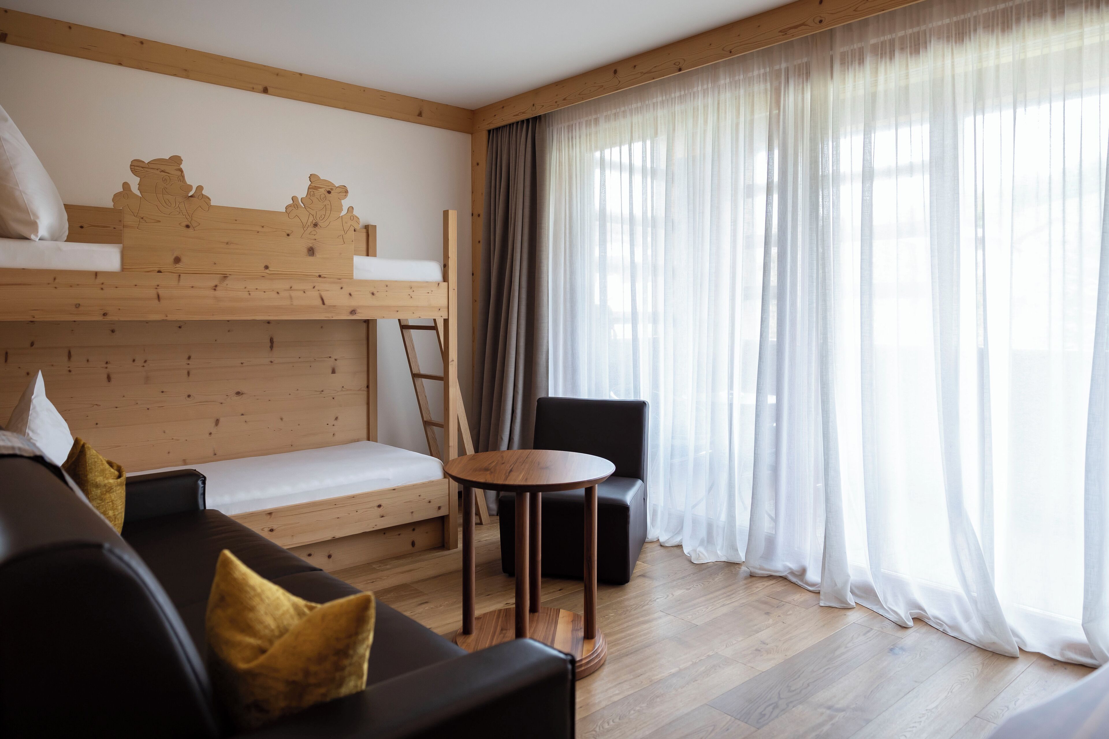 A modern room with a bunk bed, a sofa, a round table, and a chair.