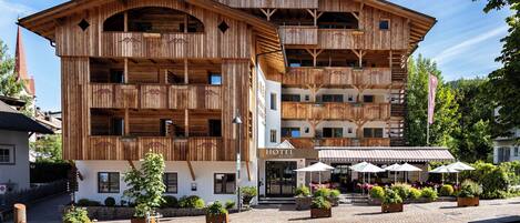 Un hotel de madera con varios balcones y un patio con mobiliario de exterior.