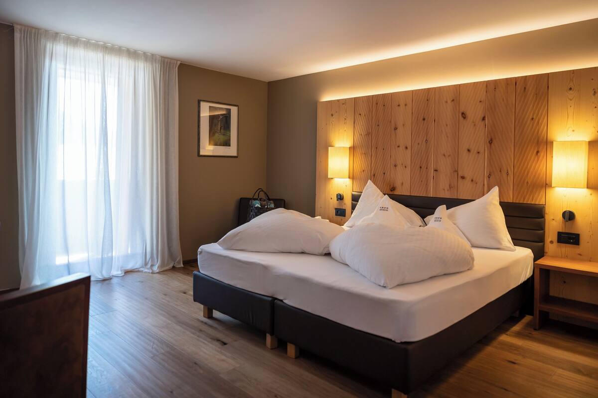 A modern bedroom with a large bed, wooden headboard, and bedside lamps.