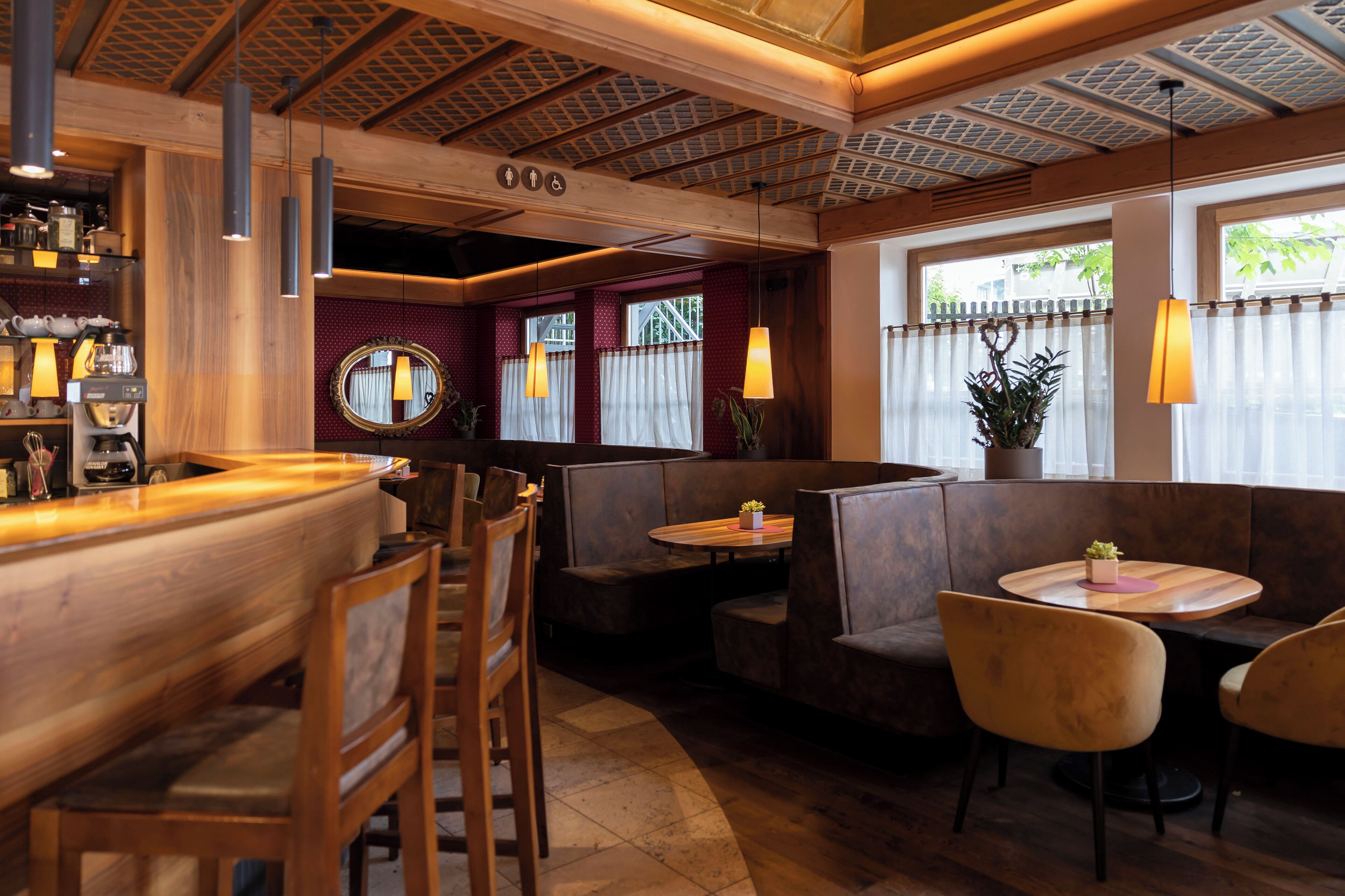 Interior de restaurante con barra de madera, cabinas y lámparas colgantes.