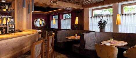Interior de restaurante con barra de madera, cabinas y lámparas colgantes.