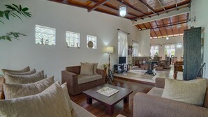 A spacious living room with a wooden ceiling, a sofa set, a coffee table, and a television. - Hanthana Holiday Rooms (Kandy)