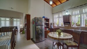 A spacious kitchen with a central island, a refrigerator with magnets, and a dining area with a table and chairs. - Hanthana Holiday Rooms (Kandy)