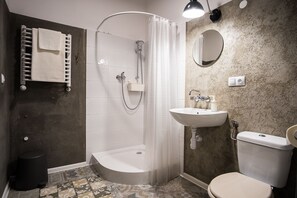A bathroom with a shower, toilet, sink, and a towel rack. - HOSTEL likeHome (Przemysl)