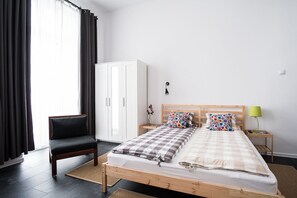 A bedroom with a bed, a chair, a wardrobe, and a nightstand with a lamp. - HOSTEL likeHome (Przemysl)