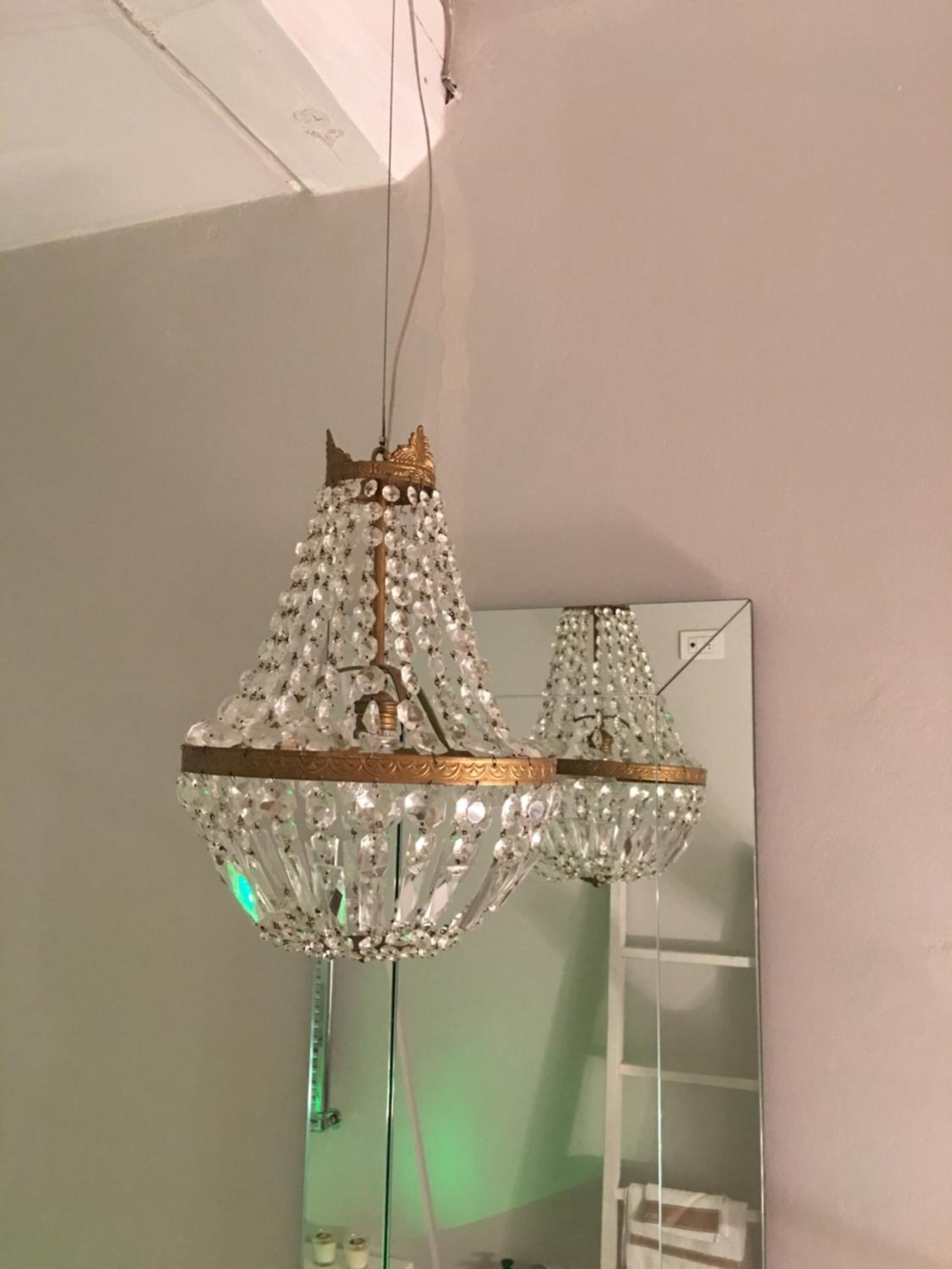 A chandelier with a gold crown and crystal decorations.