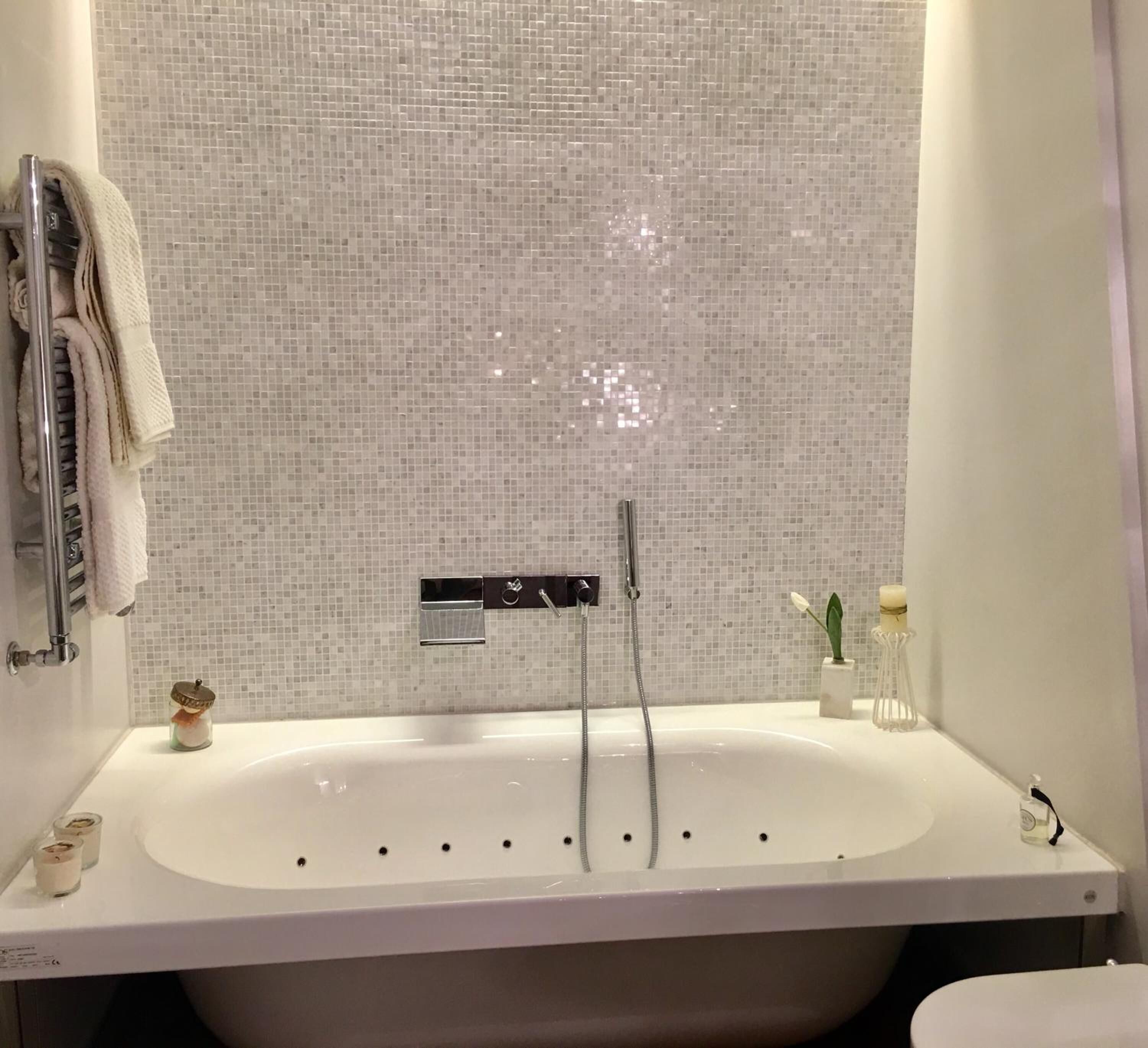 A modern bathroom with a freestanding bathtub, a showerhead, and a tiled backsplash.