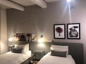 Ein Hotelzimmer mit zwei Betten, einem kleinen Tisch und Bildern an der Wand.