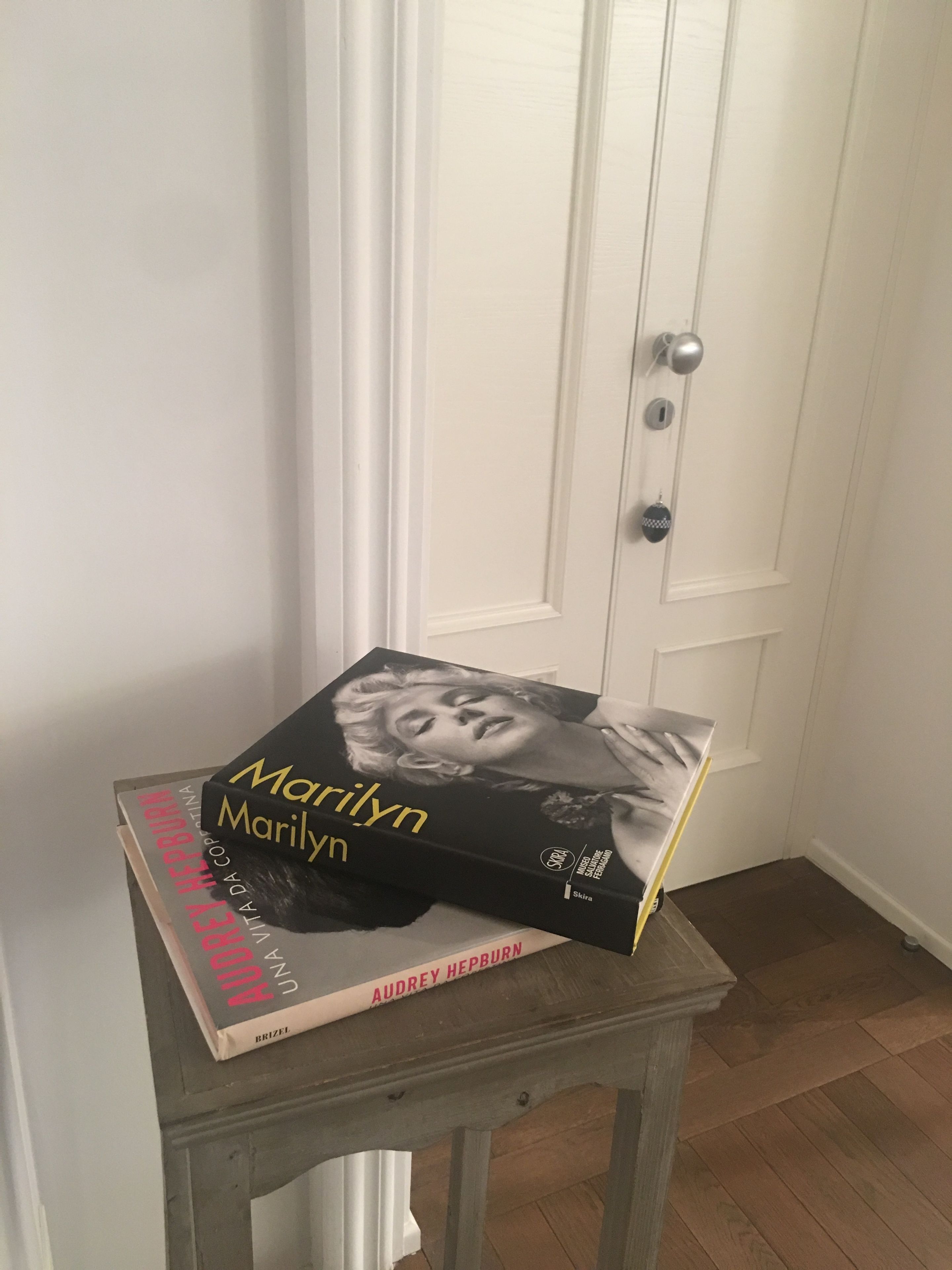 A book titled 'Marilyn' on a small wooden table in front of a white door.