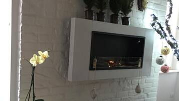 Un salon chaleureux avec un mur en briques blanches, une cheminée et une petite table décorée pour Noël.