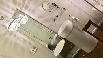 A modern bathroom with a large mirror, a round mirror, a toilet, and a sink.
