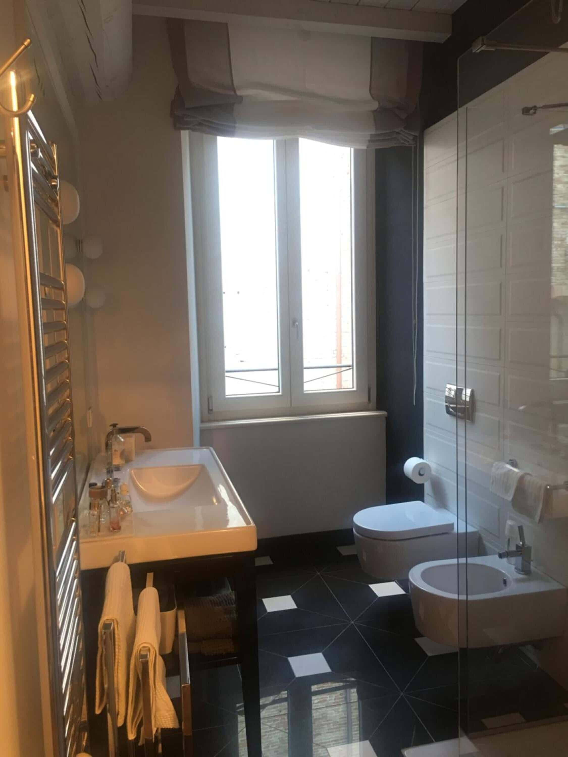 Un bagno moderno con cabina doccia in vetro, un lavandino bianco e un water.