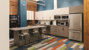 A modern kitchen with a bar area, stainless steel appliances, and a colorful striped floor. - Granville Hall Residence (Halifax)