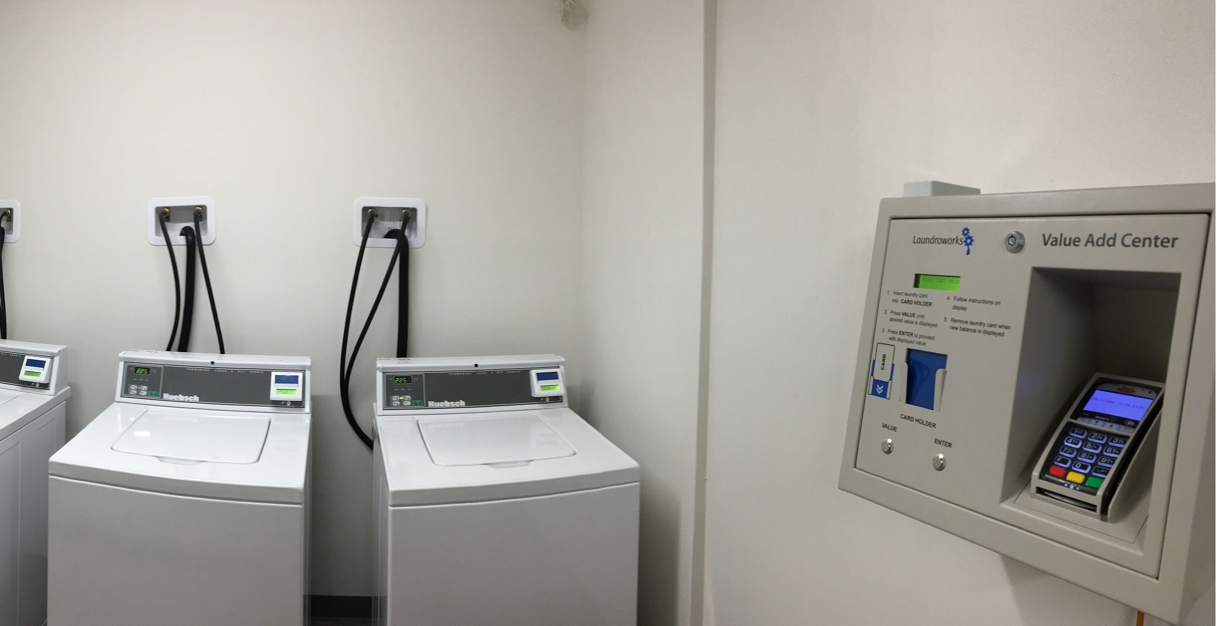 A laundromat with two front-loading washers and a card reader for payment.