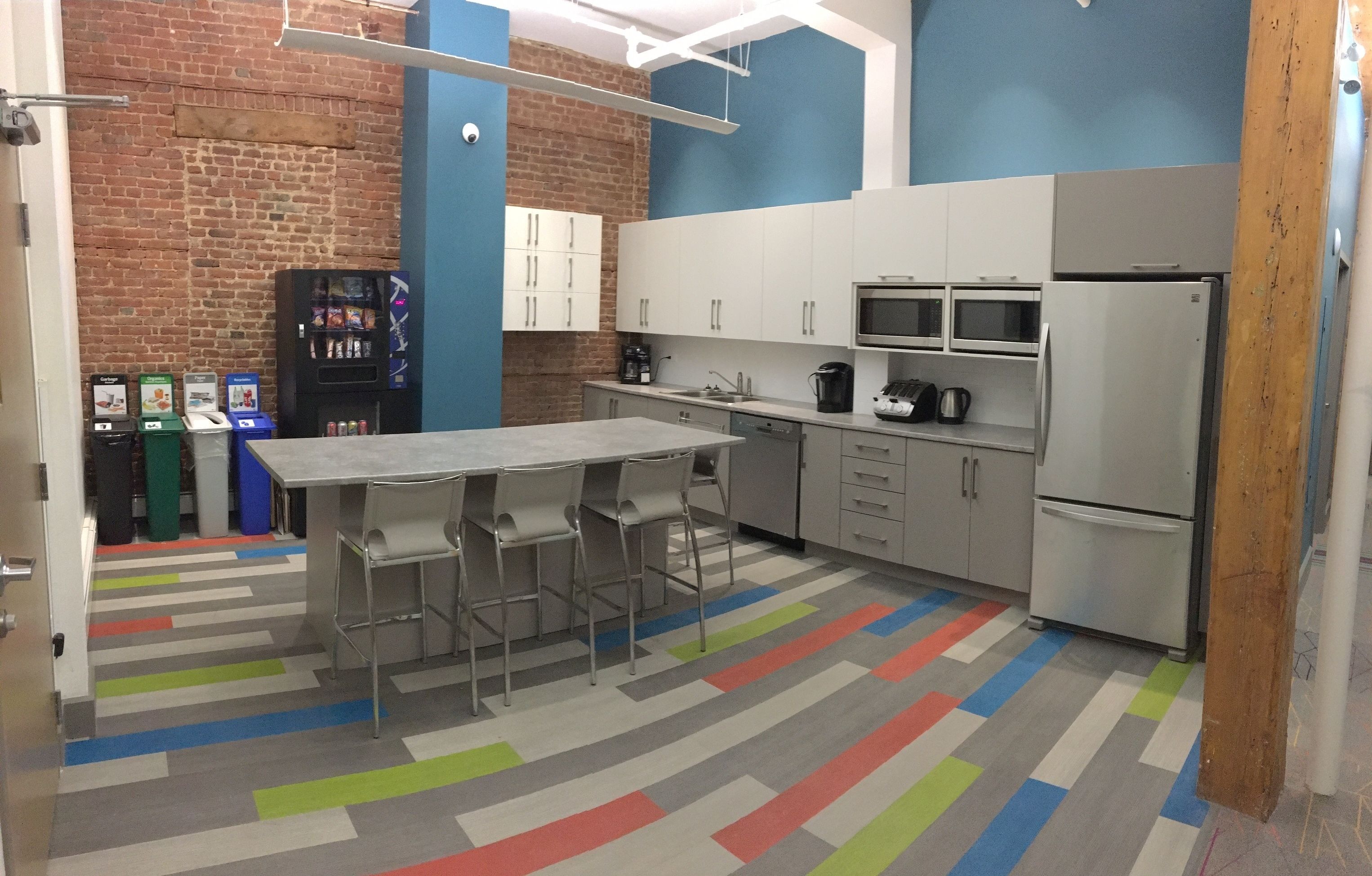 A modern kitchen with a large island, white cabinets, a microwave, and a refrigerator.