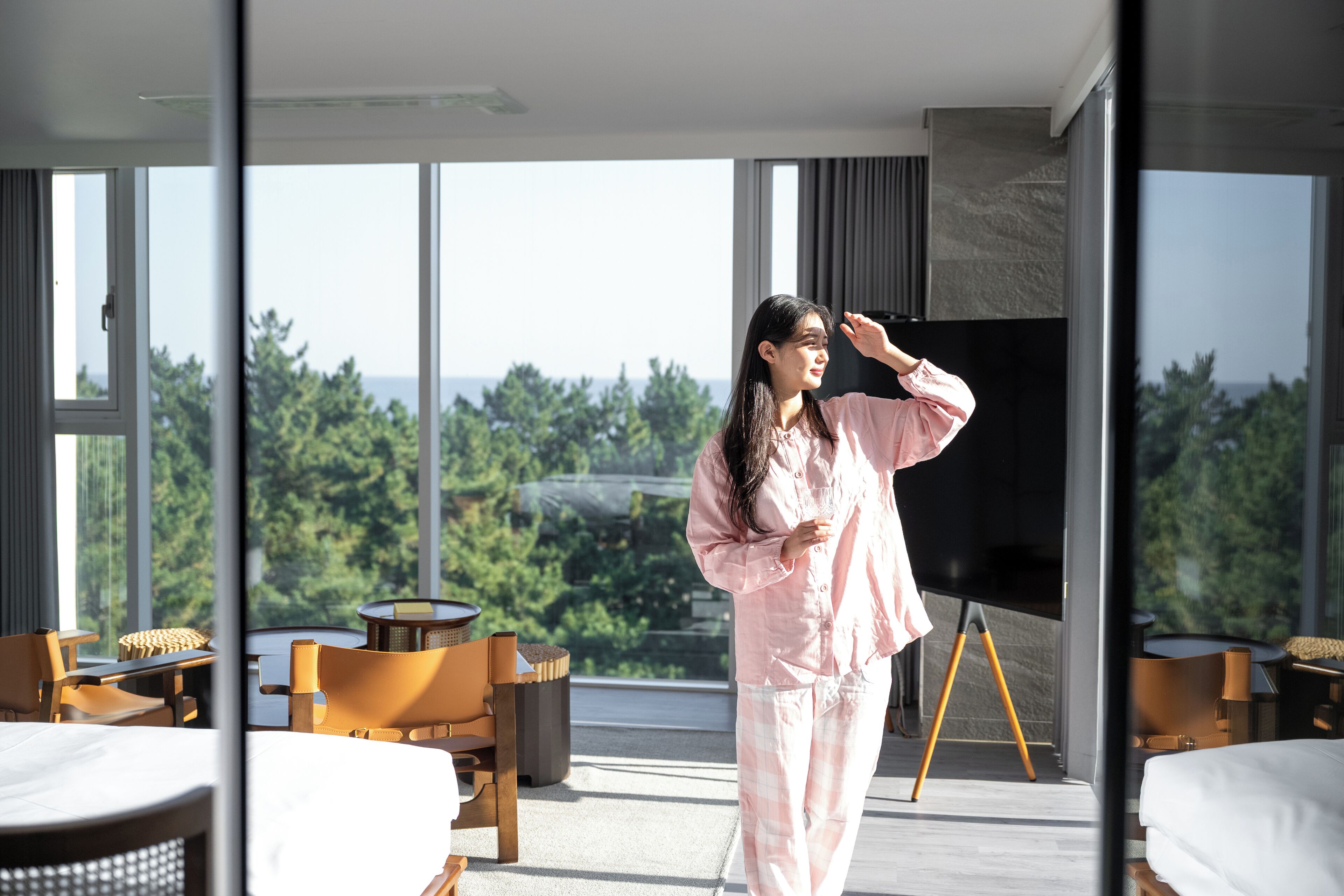 Una habitación de hotel moderna con un gran ventanal, un televisor de pantalla plana y vistas al bosque.