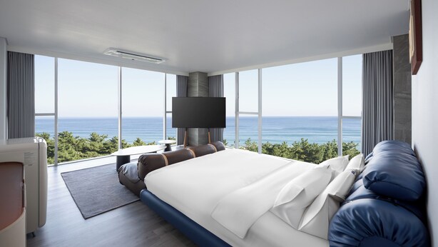 A modern hotel room with a large bed, a flat-screen TV, and a view of the ocean. - Hound The Blue (Gangneung)