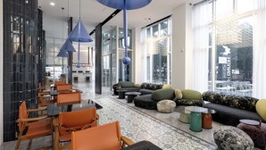 A modern hotel lobby with seating areas, tables, and large windows. - Hound The Blue (Gangneung)