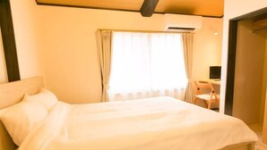 A neatly made bed in a room with a desk and chair, a window with curtains, and an air conditioning unit on the wall. - Kyo Koyado Kinkakuji Benten (Kyoto)