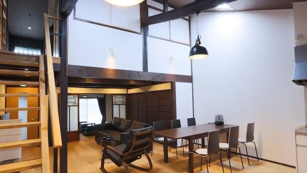 A modern interior with a dining area, a sofa, and a staircase. - Kyo Koyado Kinkakuji Benten (Kyoto)