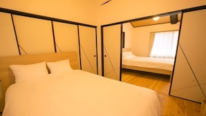 A bedroom with a large bed, a wooden floor, and a sliding door leading to another room. - Kyo Koyado Kinkakuji Benten (Kyoto)