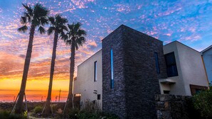 A modern building with a stone facade and a clear view of the sunset. - Marvillrick Spa&Poolvilla (Jeju City)
