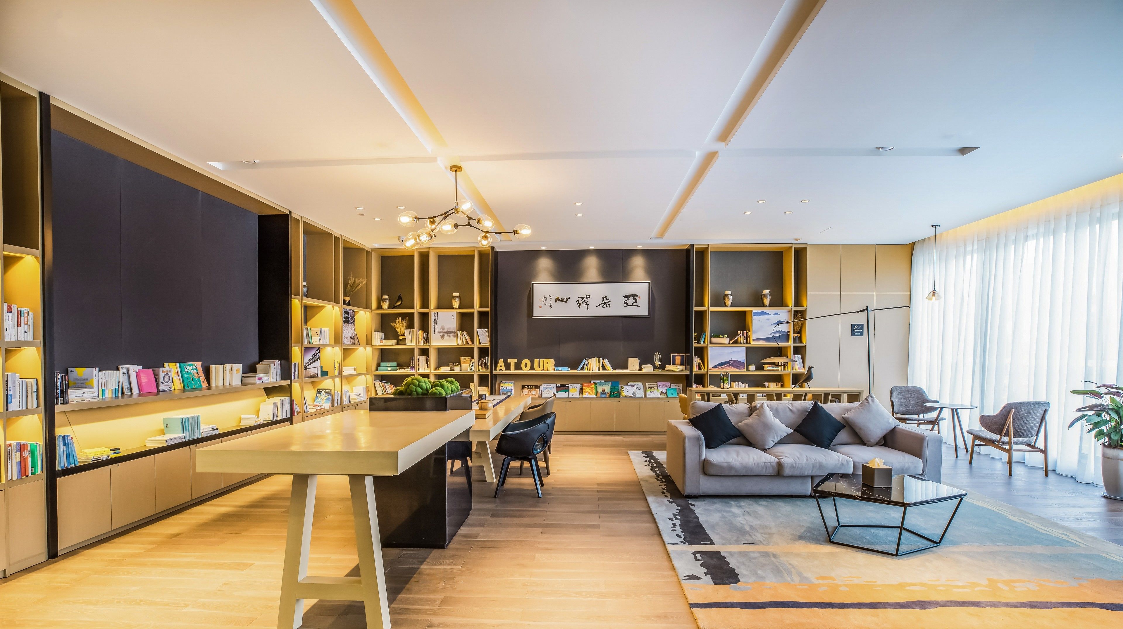 Uma sala de estar moderna com uma mesa de centro, um sofá e uma estante repleta de livros e objetos decorativos.