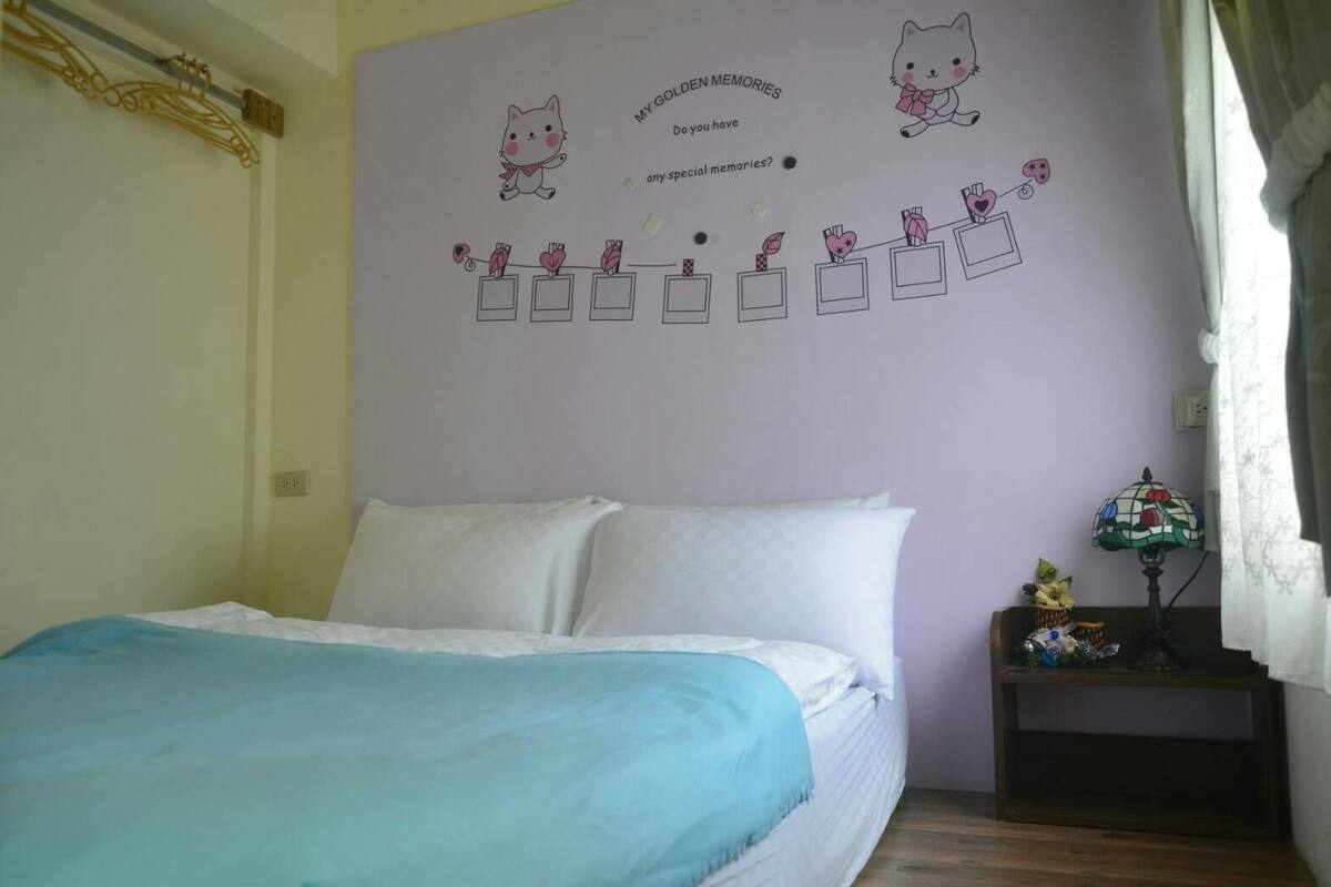 A bedroom with a bed, a wall decoration, a lamp, and a shelf with items.