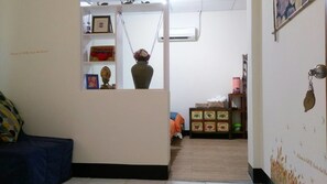 A living room with a sofa, a small table with a vase, and a shelf with various items. - Jilufugan B&B (Jinfeng)