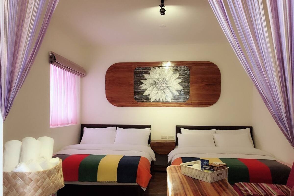 A cozy room with two beds, a wooden table, and a decorative wall piece.