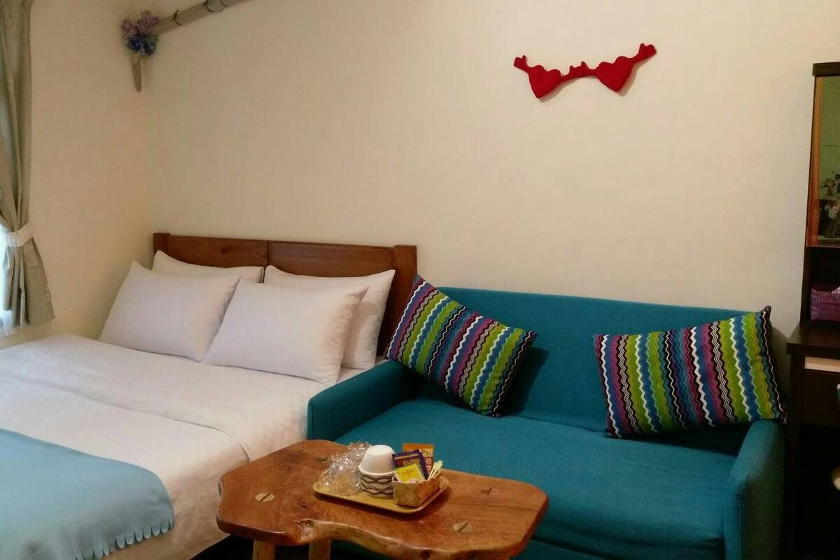 A bedroom with a bed, a blue sofa, and a wooden coffee table with snacks.
