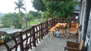 A balcony with a stone floor, wooden furniture, and a decorative fence. - Jilufugan B&B (Jinfeng)