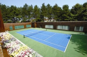 Un court de tennis avec un mur en briques et des arbres en arrière-plan.