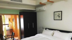 A bedroom with a bed, a wardrobe, a desk, and a chair.