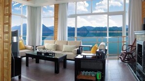 A spacious living room with a large window offering a mountain view. There is a sofa, a coffee table, and a fireplace.