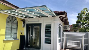 A building with a glass roof, a black door with vertical bars, and a yellow wall. - H & H Guesthouse 1 (Malacca City)