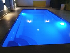 A pool with a blue floor and four illuminated lights.