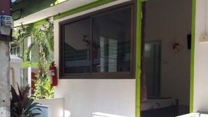 A building with a green and white facade, a window, and a fire extinguisher mounted on the wall. - Sukhothai Bungalow (Cha-am)