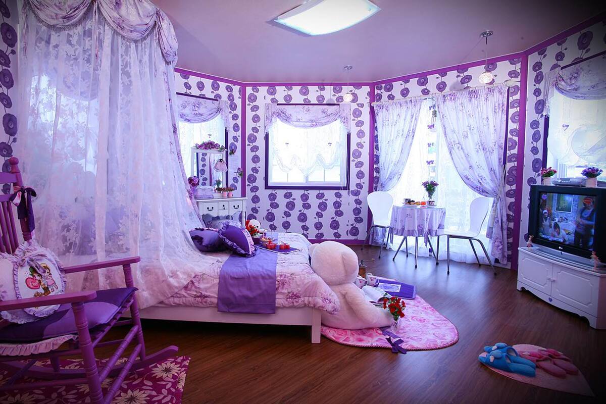 Quarto com cama, cadeira, escrivaninha e televisão.