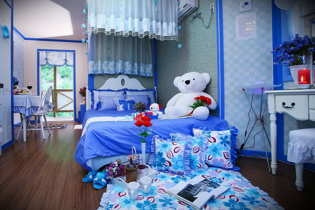 Quarto com cama, um urso de pelúcia e uma escrivaninha com cadeira.