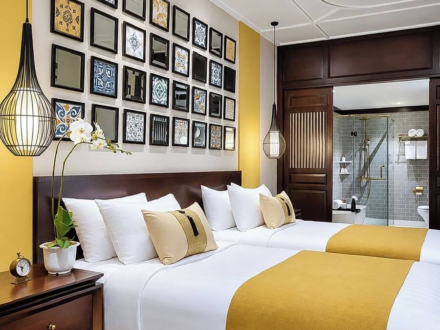 A hotel room with a large bed, a bedside table, a wall with framed artwork, and a bathroom with a shower and toilet.