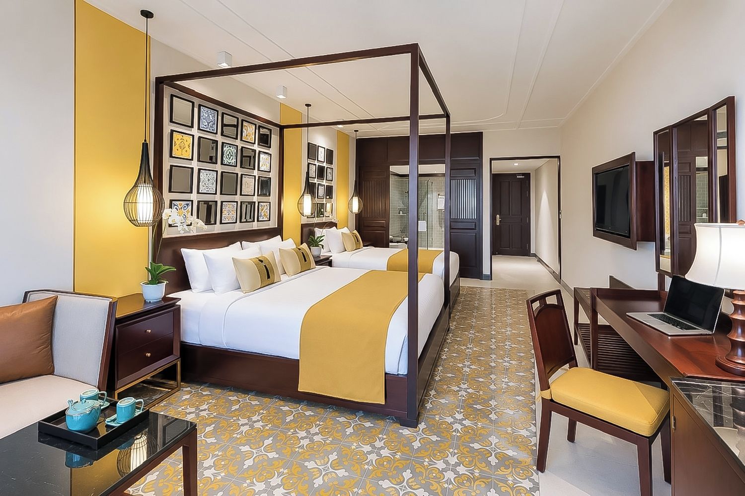Ein Hotelzimmer mit Himmelbett, Schreibtisch, Laptop, Stuhl und Fernseher.