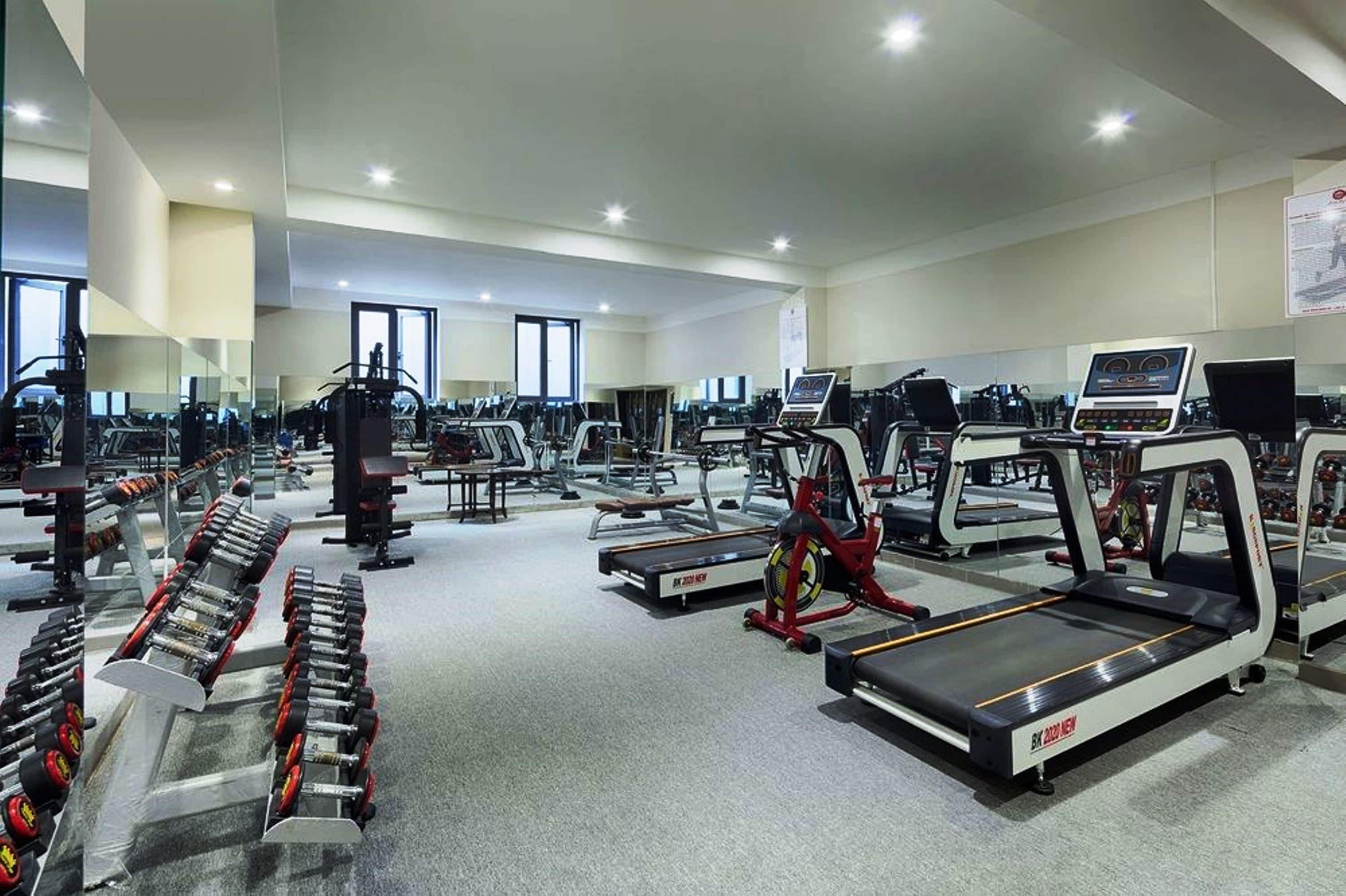 Une salle de sport spacieuse équipée de tapis de course, d’appareils de musculation et de poids libres.