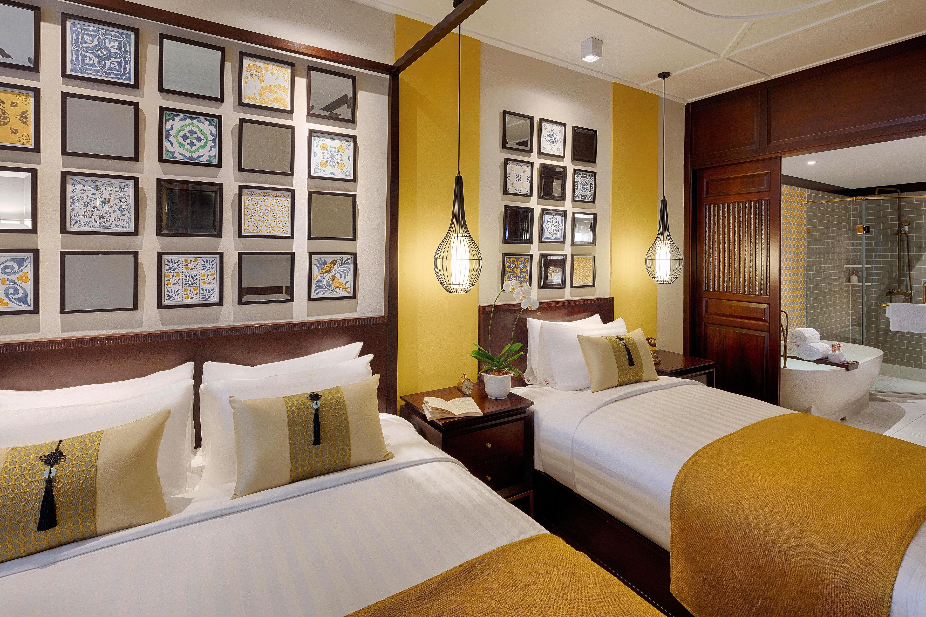Une chambre d’hôtel avec deux lits, une table de chevet avec une horloge et une plante, et une salle de bain avec une douche et un lavabo.