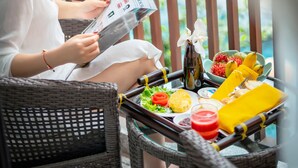 Una mujer sentada en una silla de mimbre junto a una mesa con comida y un menú.