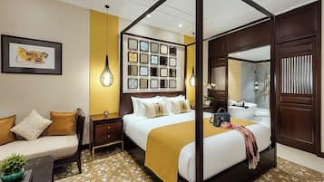A four-poster bed with a gold throw blanket, a bedside table with a lamp, and a framed picture on the wall.
