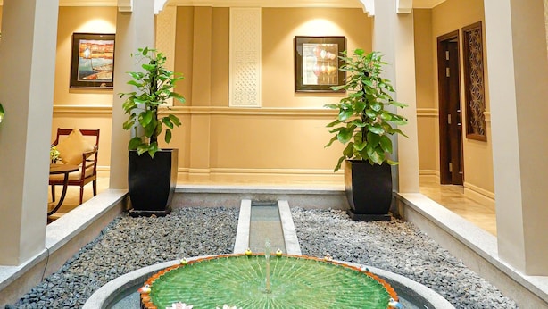 A spacious atrium with a central water feature, two potted plants, and a balcony with a railing. - Allegro Hoi An. A Little Luxury Hotel & Spa (Da Nang)