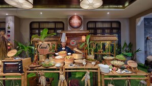 Un puesto de mercado tradicional con diversos productos alimenticios y un cocinero con uniforme.