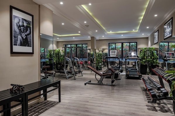 Un gimnasio con diferentes equipos de ejercicio, una banca y una cinta de correr.